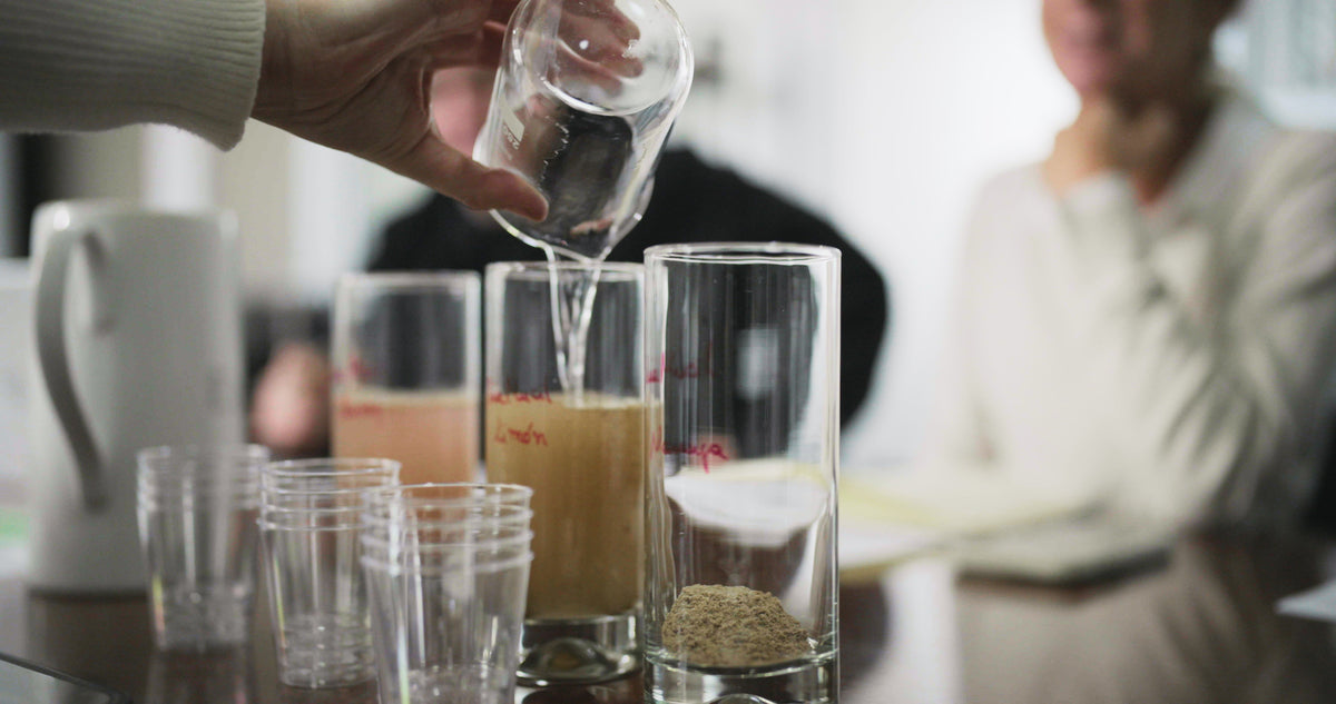 Water being poured into a glass of dry fiber, beside glasses of fiber already mixed with water