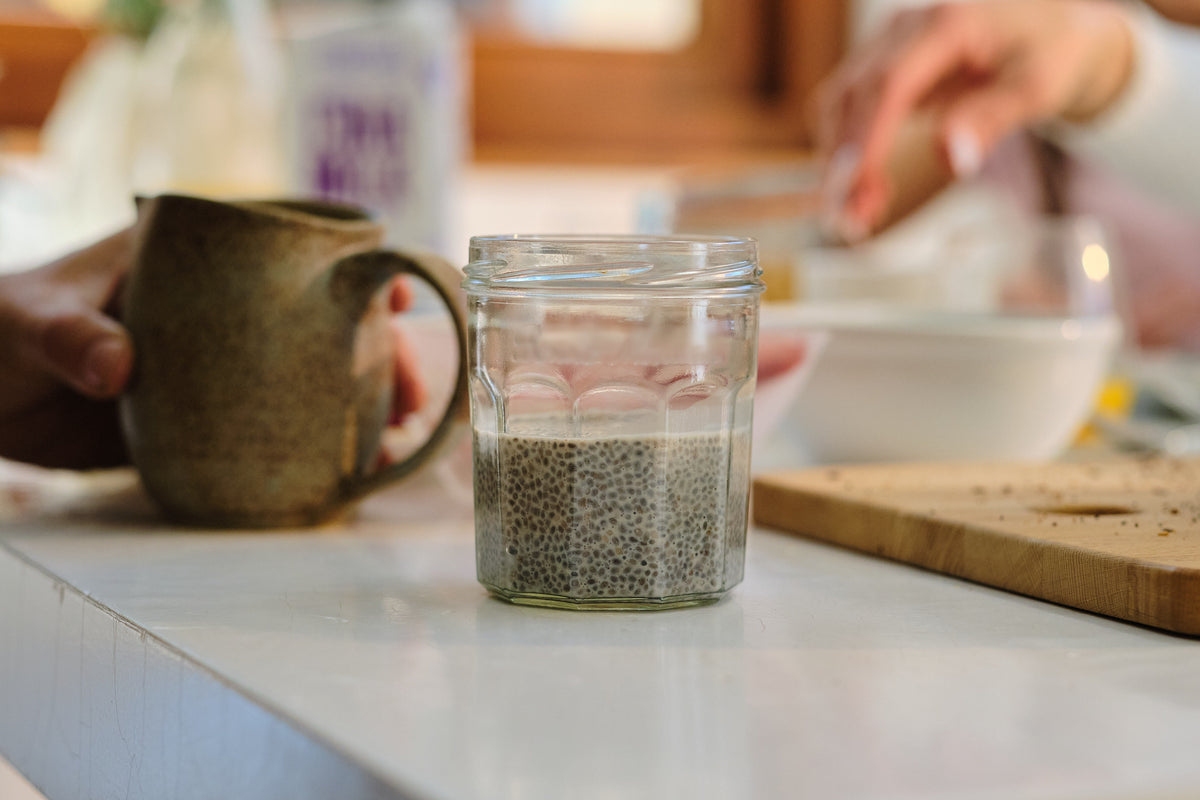 A glass jar of chia seeds soaked in water on a kitchen counter